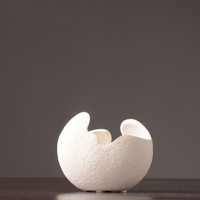 Single white ceramic vase showing its curved form and uneven open rim